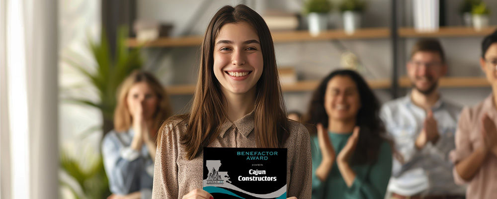 Young woman holding an acrylic plaque she was presented as a benefactor award.